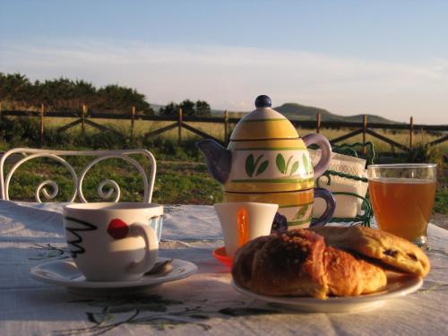 a table with a tea pot and coffee and pastries at Roccabianca in Sorso