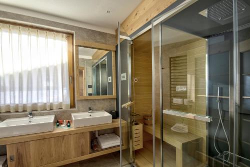 a bathroom with two sinks and a glass shower at Dolomiti Lodge Alverà in Cortina dʼAmpezzo