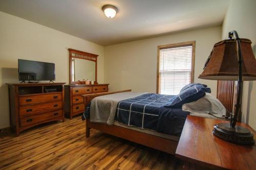 a bedroom with a bed and a dresser and a television at Green Castle cabin on the Shenandoah River in Oak Hill
