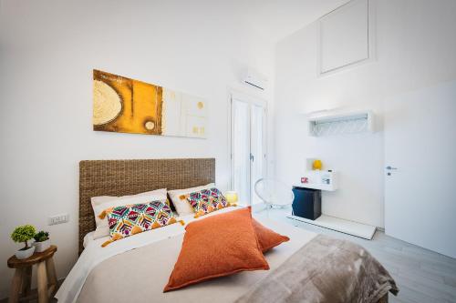 a white bedroom with a bed with orange pillows at La casa di Giovanni in Lecce