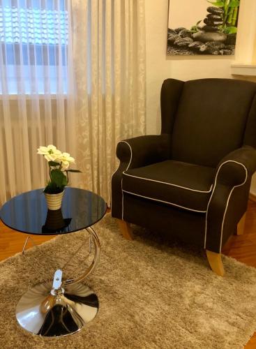 a living room with a chair and a glass table at Wilsmann Apartmentvermietung in Hövelhof