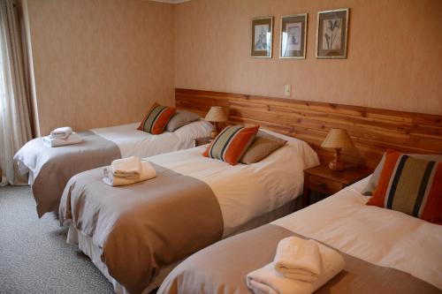 Habitación de hotel con 3 camas y toallas. en Hotel Borde Lago, en Puerto Varas