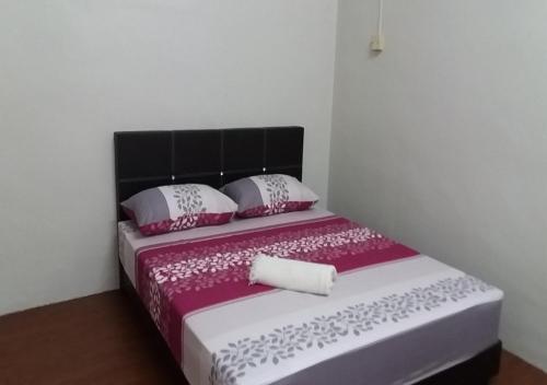 Bett mit rosa und weißer Bettwäsche und Kissen in der Unterkunft Batu Berendam Homestay in Malakka