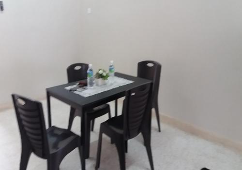 a table with three chairs and a black table and chairs at Batu Berendam Homestay in Melaka