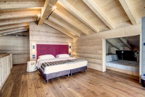 a bedroom with a bed in a room with wooden walls at Dolomiti Lodge Alverà in Cortina dʼAmpezzo