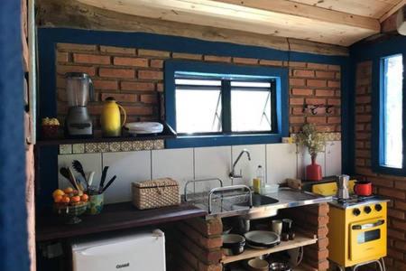 a kitchen with a yellow stove and a brick wall at sítio cambará in Aiuruoca