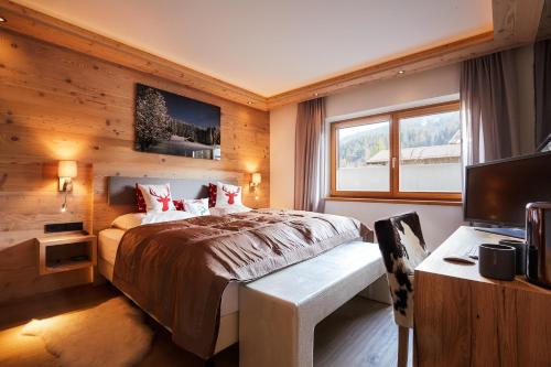 um quarto com uma cama, uma secretária e uma televisão em Top modernes Ferienhaus mit Sauna! Nicht weit vom Skilift em Kirchberg in Tirol