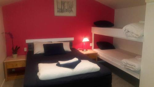 1 dormitorio con 2 literas y pared roja en Hotell Milano, en Åstorp