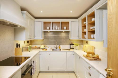 a white kitchen with white cabinets and a sink at The Hazel in Doolin