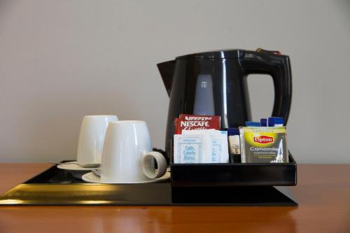 a coffee maker and cups on a table at Gran Hotel Albacete in Albacete