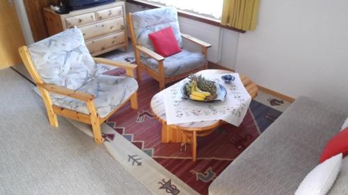 a living room with two chairs and a table with a bowl of bananas at Casa Collina in Disentis