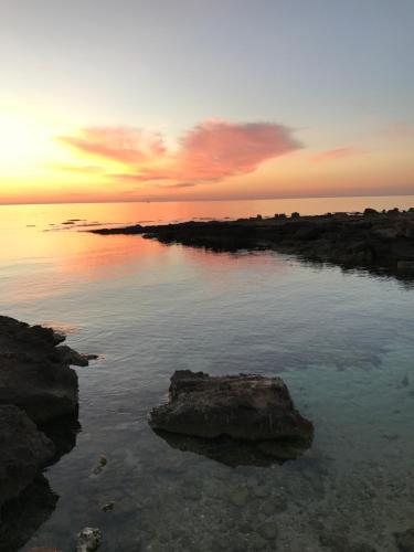 a sunset over the ocean with rocks in the water at Room 86 in San Vito lo Capo