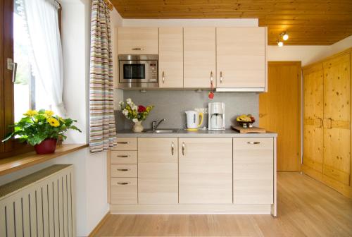 cocina con armarios blancos y microondas en Haus Christl, en Reit im Winkl