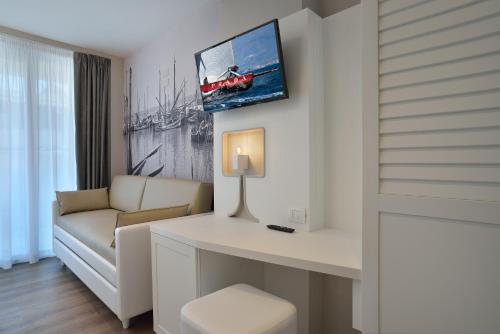 a living room with a couch and a tv on the wall at Embassy Hotel & Spa in Cattolica