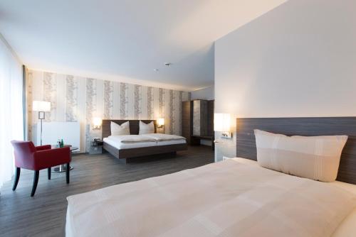 1 dormitorio con 1 cama blanca y 1 silla roja en Hotel Westermann en Osnabrück
