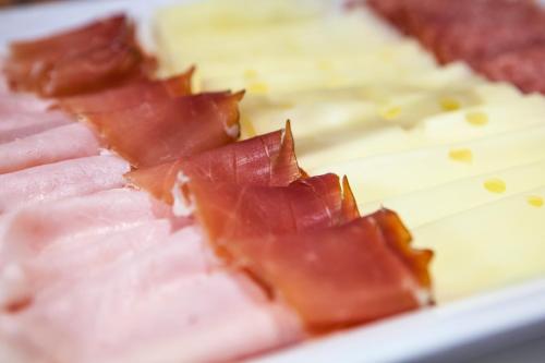 a plate of food with ham and cheese at Garni La Majon in Selva di Val Gardena