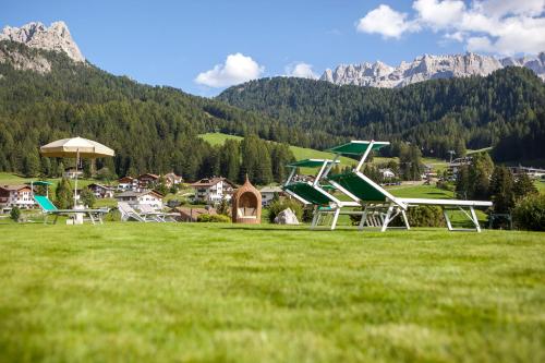 a group of picnic tables in a field with mountains at Garni La Majon in Selva di Val Gardena