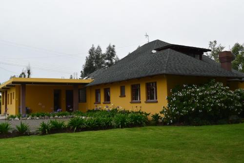 a yellow house with a lawn in front of it at Casa de Campo in Cayambe