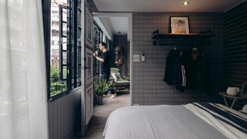 a man is looking out the window of a bedroom at Little Apartment A+B Welcome Taipei Long Stay in Taipei