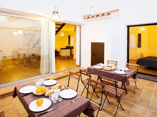 a dining room with two tables and a living room at Casa Babel Monfragüe in Torrejón el Rubio