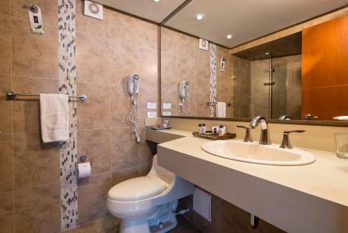 a bathroom with a sink and a toilet and a mirror at Hotel Dann Cartagena in Cartagena de Indias