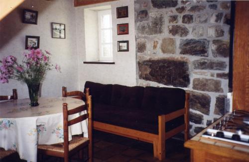 een eetkamer met een tafel en een stenen muur bij Le moign-locations in Camaret-sur-Mer