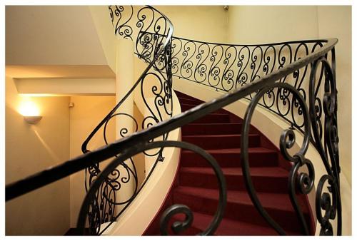 a staircase with a wrought iron railing in a building at Piwnica Rycerska Kęty in Kęty