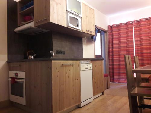 a kitchen with wooden cabinets and a white refrigerator at T2 RESIDENCE ANTARES 4* pieds des pistes in Risoul