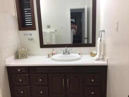 a bathroom sink with a mirror and a person taking a picture at Buccaneer Beach Club in Dickenson Bay