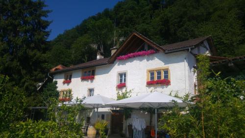 ein weißes Gebäude mit Sonnenschirmen davor in der Unterkunft Ferien auf dem Weingut in Ligerz