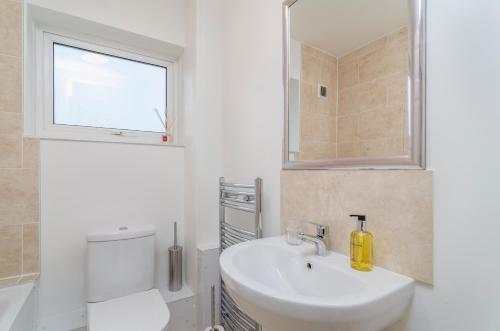 a bathroom with a sink and a toilet and a window at Saffron - Heathrow-Airport-with Parking in Feltham