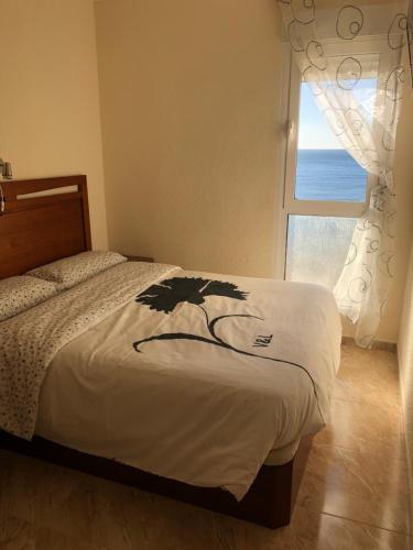 a bedroom with a bed and a window with the ocean at Playa Los Locos - Coloso in Torrevieja