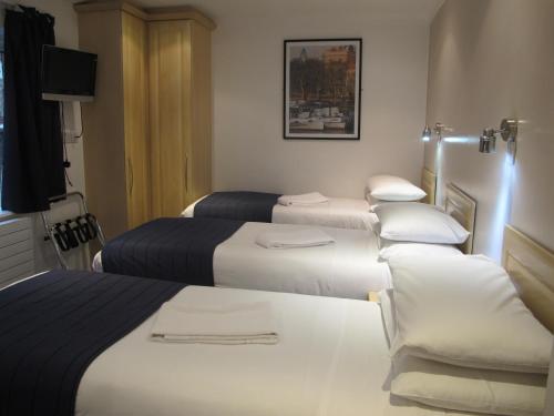 a hotel room with four beds and a television at Alhambra Hotel in London