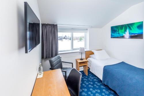 Cette chambre comprend un lit, un bureau et une table. dans l'établissement Litli Geysir Hotel, à Haukadalur