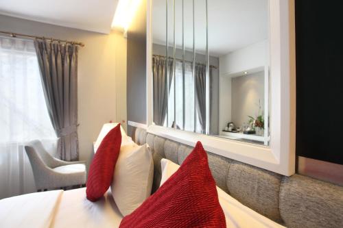 a hotel room with a bed with red pillows and a mirror at Gino Feruci Braga by KAGUM Hotels in Bandung