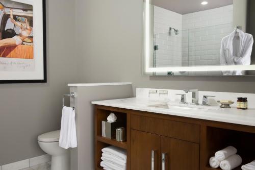 a bathroom with a sink and a toilet and a mirror at Hotel ZaZa Houston Memorial City in Houston
