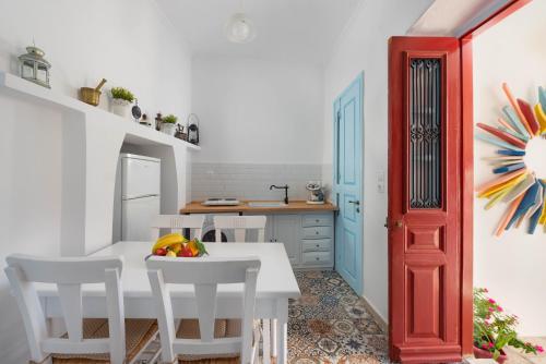 a kitchen with a white table and chairs and a red door at Castello Venetsiana in Symi