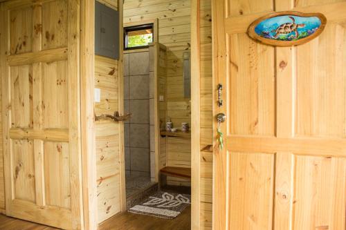 a door to a bathroom with a shower in a log cabin at Forest Lodge in Uvita