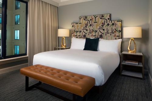 a hotel room with a large bed and a bench at Hotel ZaZa Houston Memorial City in Houston