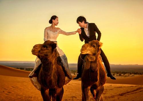 a man and woman riding a camel in the desert at Luxurious Merzouga Desert Camps in Merzouga