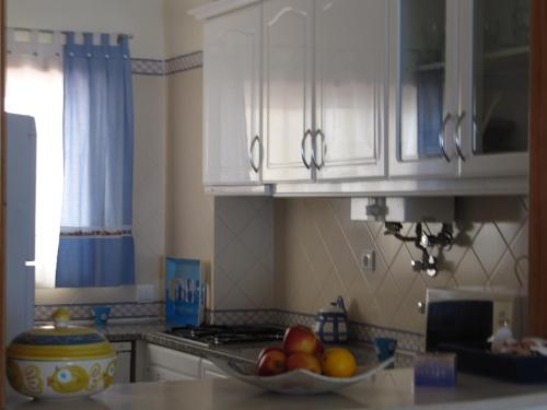 a kitchen with white cabinets and a bowl of fruit on a counter at Apartamento Clube do Vau in Portimão