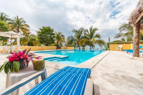 a swimming pool with blue benches and palm trees at Casa Bonita and villas in Isla Mujeres