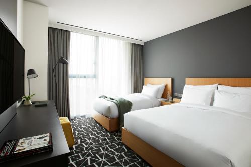 a hotel room with two beds and a desk at L7 GANGNAM by LOTTE in Seoul