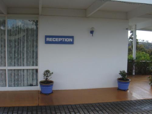 Kingfisher Motel (Adults only) في ميريمبولا: مبنى ابيض به مزرعتين و لافته