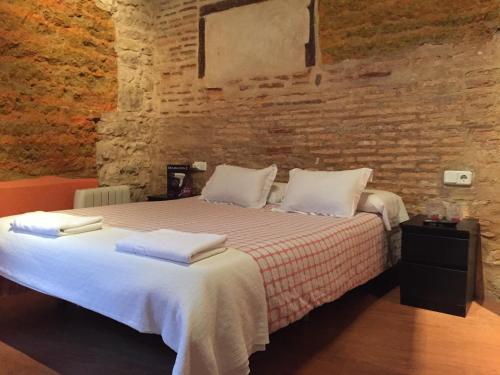 1 dormitorio con 1 cama grande en una pared de ladrillo en Hosteria Natura Plaza, en Segovia