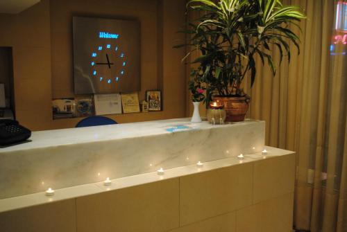 a reception desk with a clock and a potted plant at Hotel Ideal in Piraeus