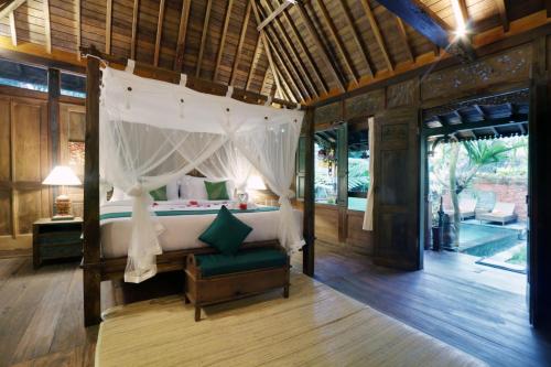 a bedroom with a canopy bed in a room at Honeymoon Green Villa in Ubud