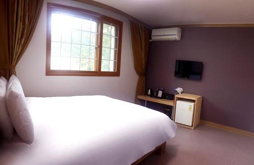 a bedroom with a large white bed and a window at Muju Rejortel in Muju