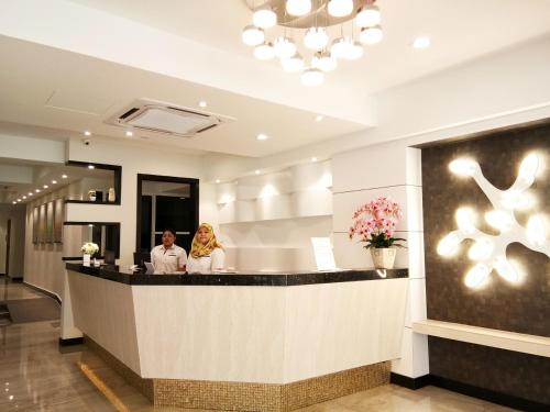 two people standing at a counter in a hotel lobby at Meriton Inn in Kuantan