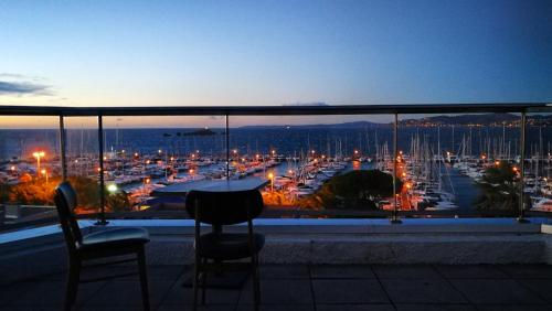 a balcony with a view of a harbor at night at Hotel Brise de Mer - Piscine intérieure & extérieure in Saint-Raphaël